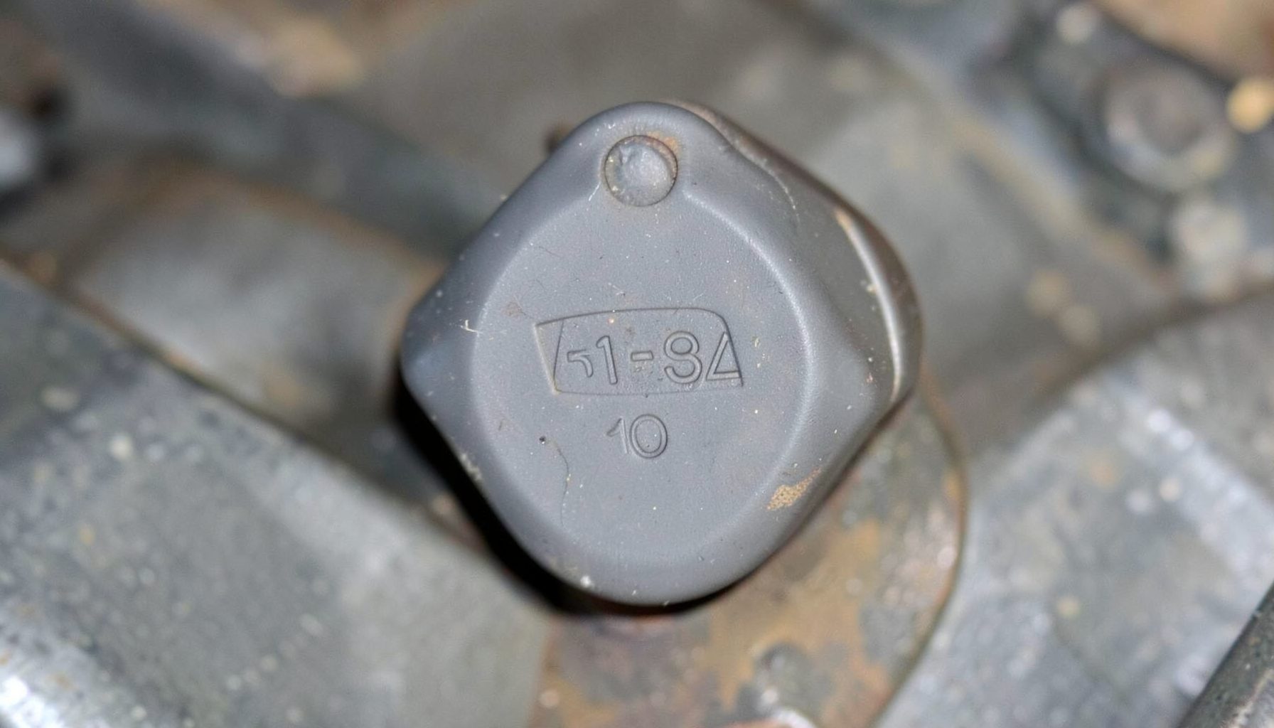 Small livestock ear tag component with a marked identification number, matte plastic and metal tones, agricultural equipment feel