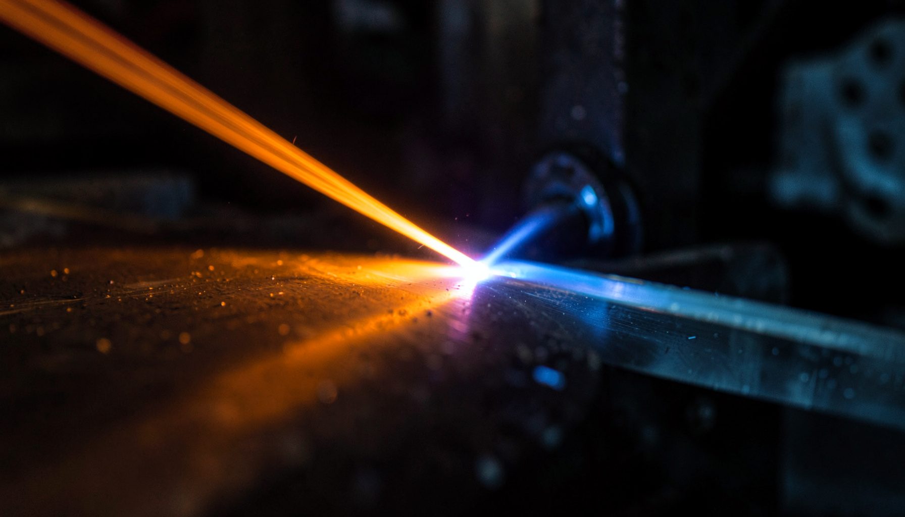 Abstract close-up of a laser beam striking a metallic surface, with warm orange and cool blue reflections against a dark industrial background