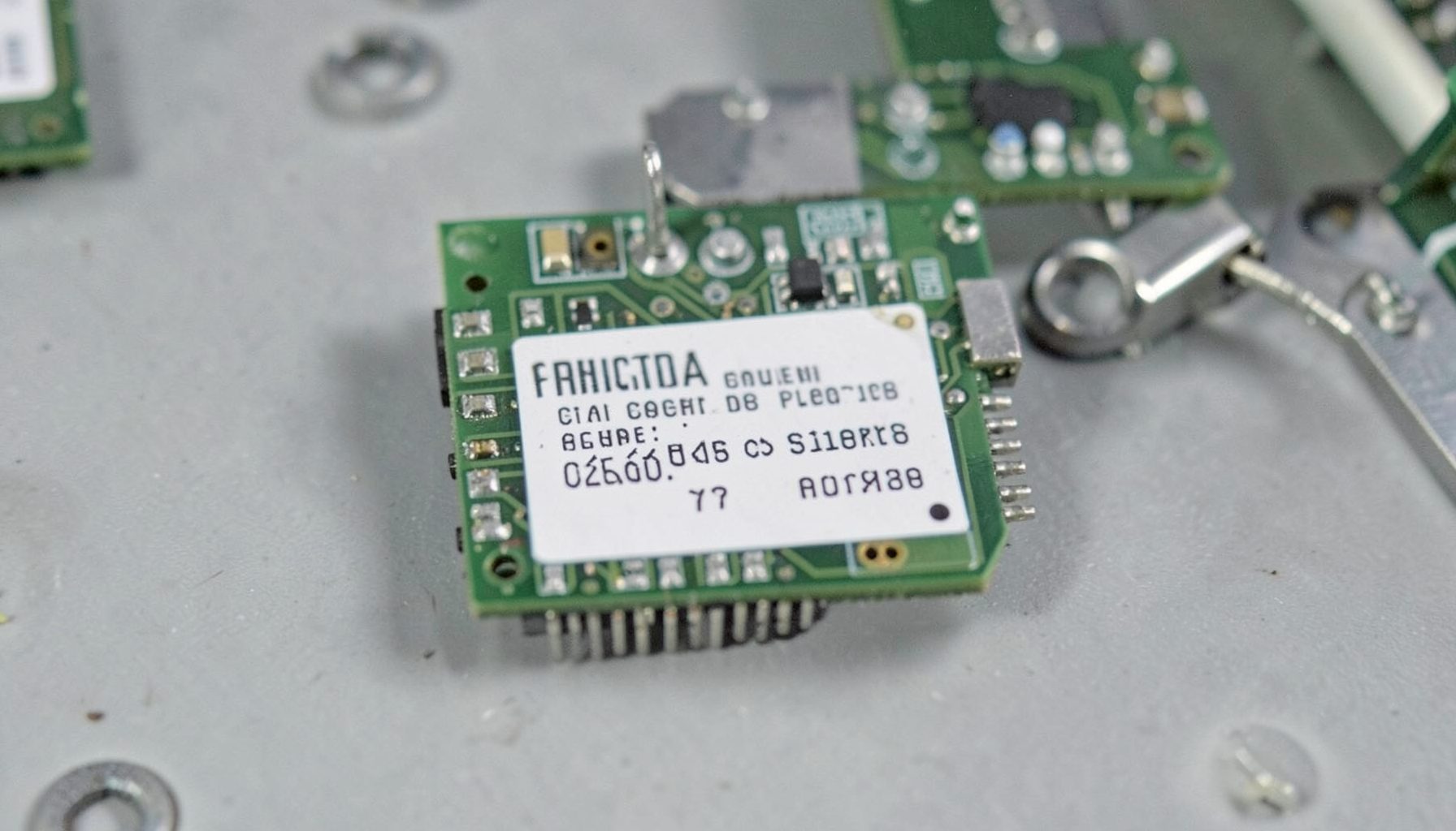 Small circuit board with a printed label area, muted green and gray tones, orderly electronics assembly setting