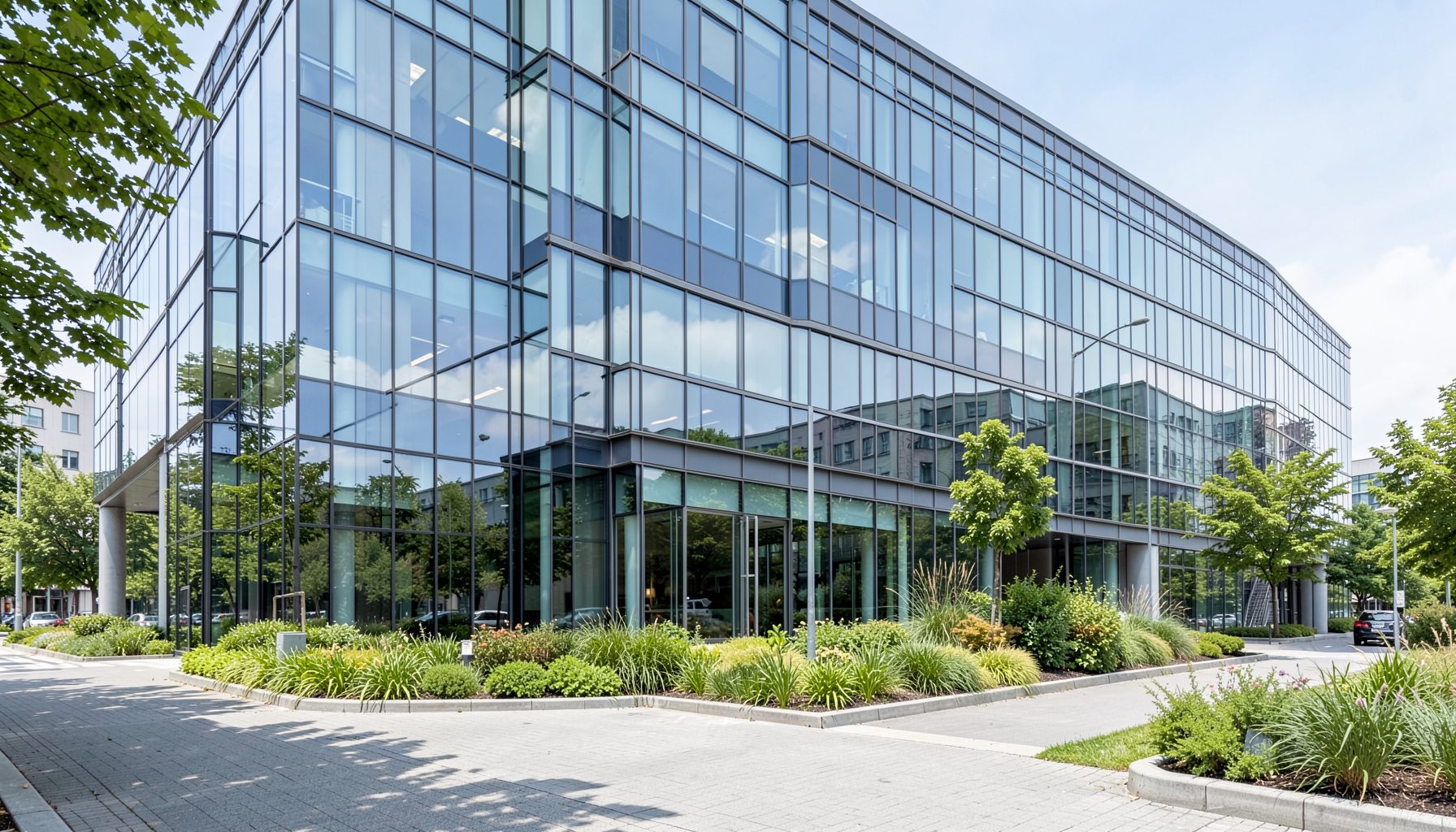 Modern industrial office building exterior with glass facade and green landscaping, conveying a professional corporate atmosphere